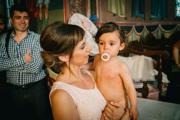 Experience the pure joy of motherhood: A mother holds her smiling baby after a summer christening in Athens.