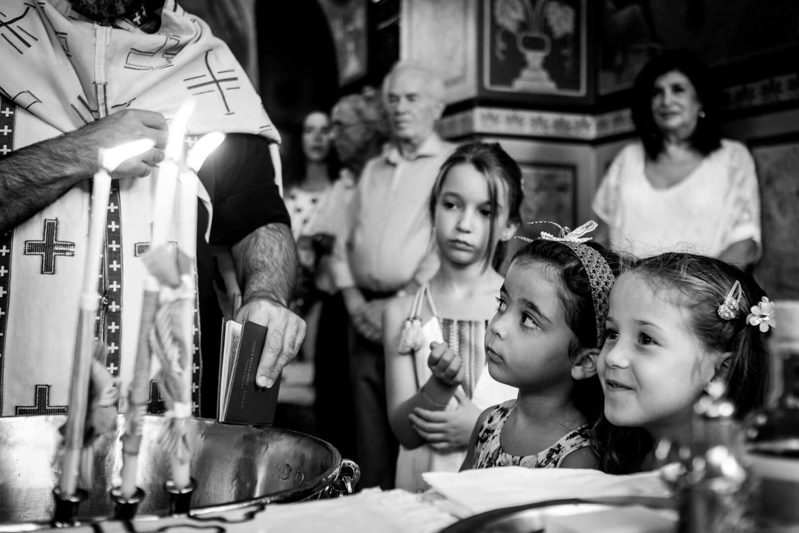 Wide-eyed wonder: children observe the priest blessing water during a religious ceremony.
