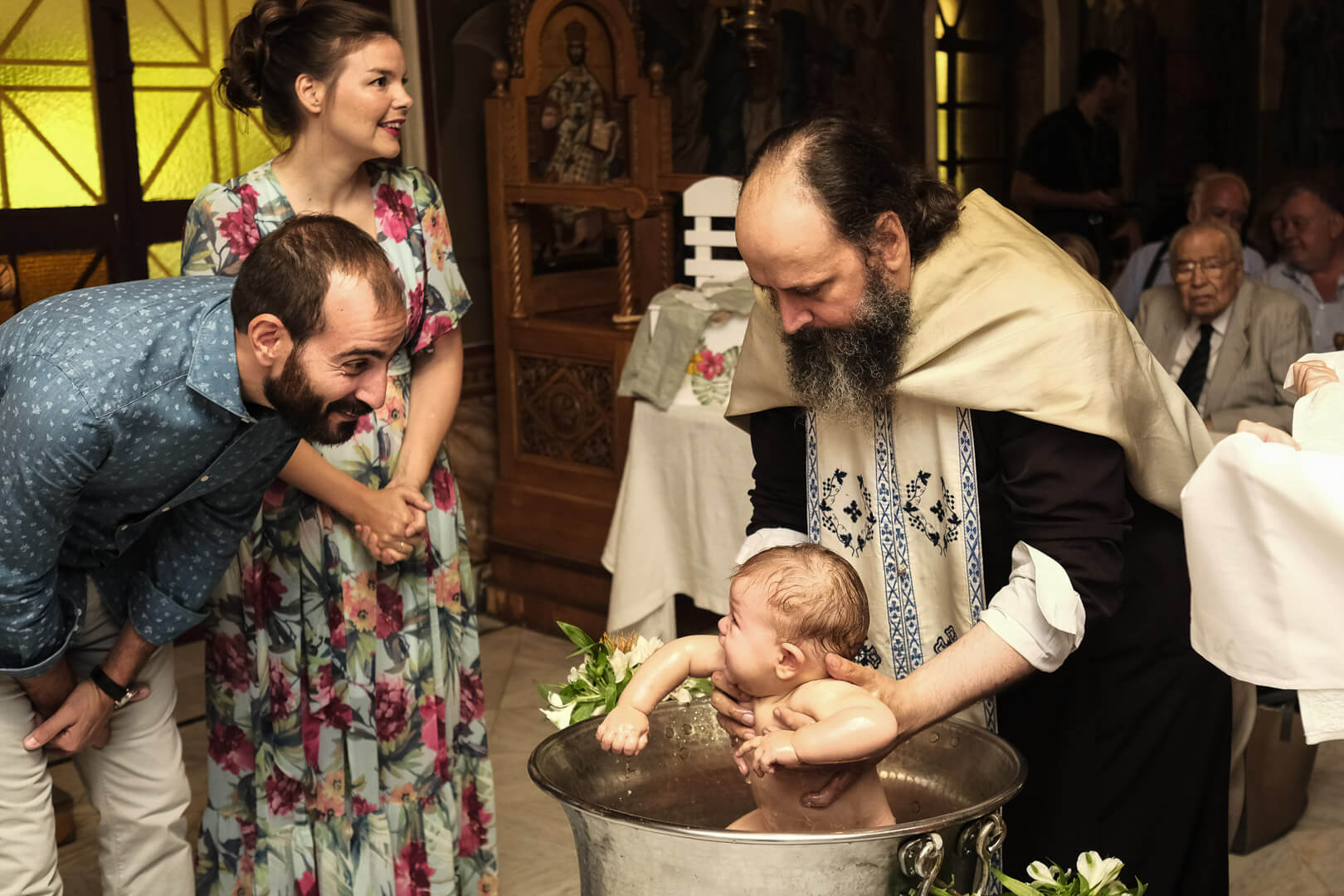 Greek christening celebration: Father beams with love as his child receives blessings.