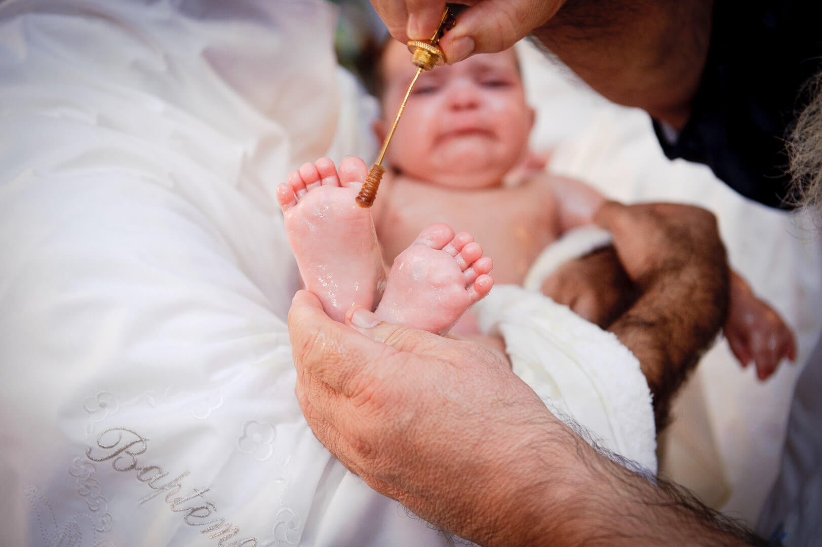 Sacred rite unfolds: Priest performs anointing with holy oil during a christening ceremony.