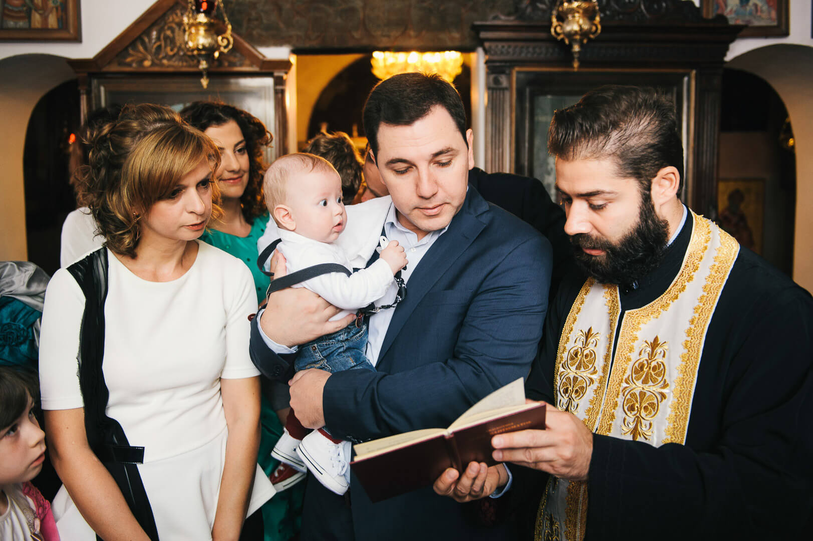 Meaningful christening moment: godfather leads blessings with care, priest guides the ceremony.