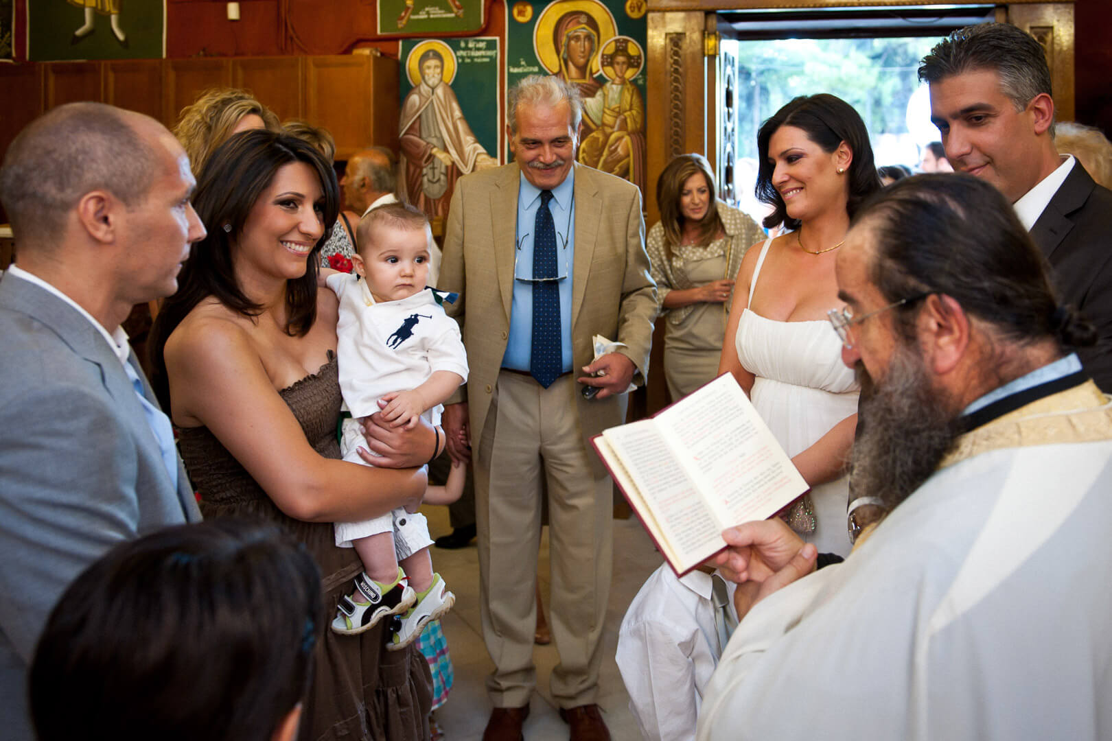 Family love and faith unite: beaming baby rests in mother's arms during christening blessings. 