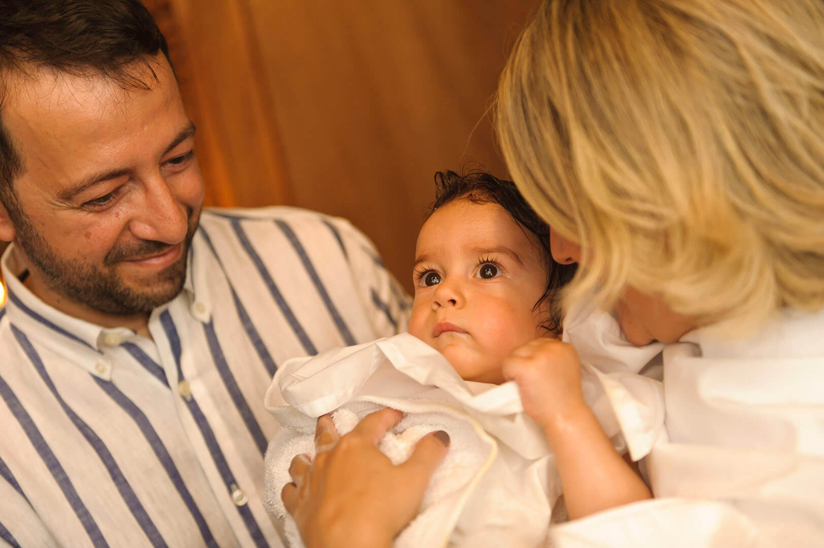 Joyful family moment: Tenderness fills the air as parents embrace their baptized child.