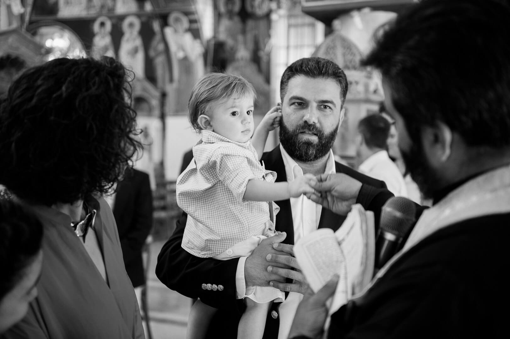 Tender moment during blessings: father holds child close as sacred words are spoken during the christening.