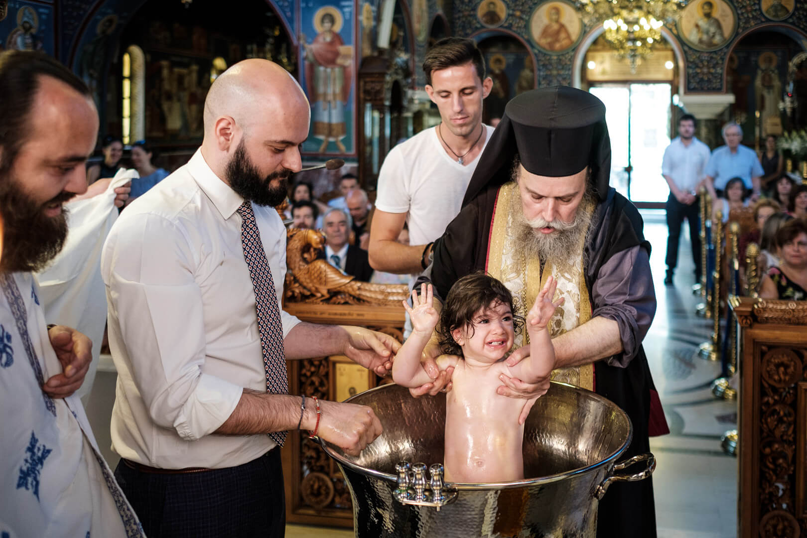 Joyful christening moment: baby smiles happily as holy water is poured during the ceremony.